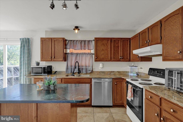 kitchen with appliances with stainless steel finishes, sink, a center island, and light tile patterned floors