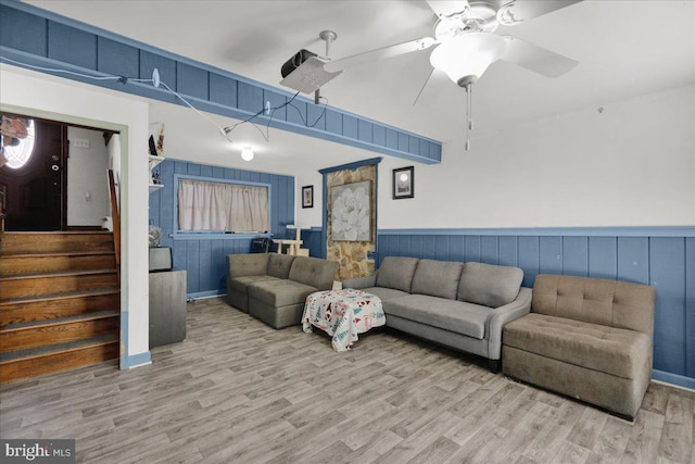 living room featuring wood walls, ceiling fan, and light hardwood / wood-style flooring