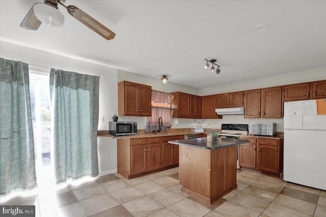 kitchen with light tile patterned flooring, a kitchen island, sink, white appliances, and ceiling fan