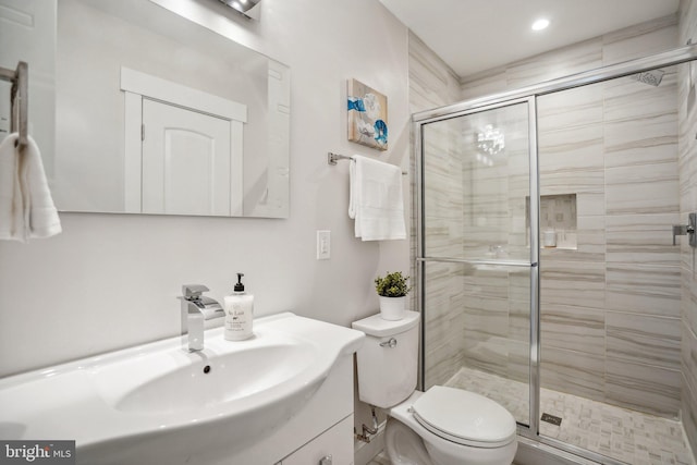 bathroom featuring a shower with shower door, vanity, and toilet