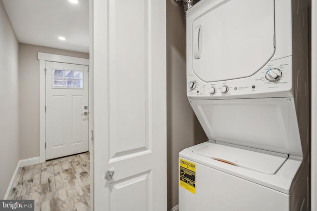 laundry area with light hardwood / wood-style floors and stacked washer / drying machine