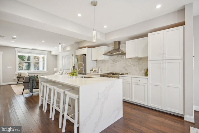 kitchen with dark hardwood / wood-style flooring, white cabinetry, wall chimney range hood, and decorative light fixtures