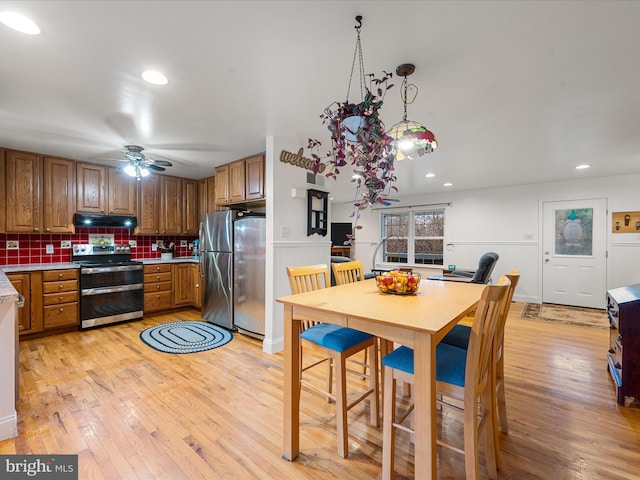 kitchen featuring decorative backsplash, appliances with stainless steel finishes, ceiling fan, light hardwood / wood-style floors, and hanging light fixtures