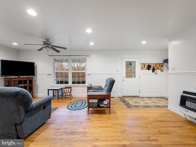 living room featuring heating unit, ceiling fan, and light hardwood / wood-style flooring