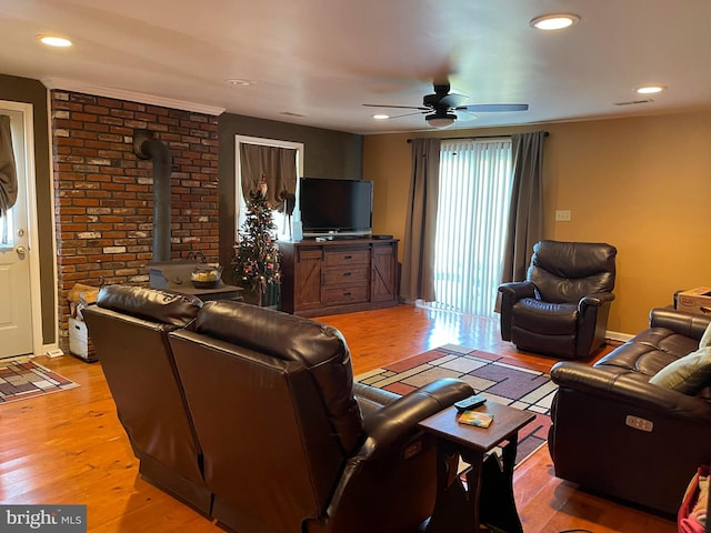 living room with a wood stove, hardwood / wood-style flooring, and ceiling fan