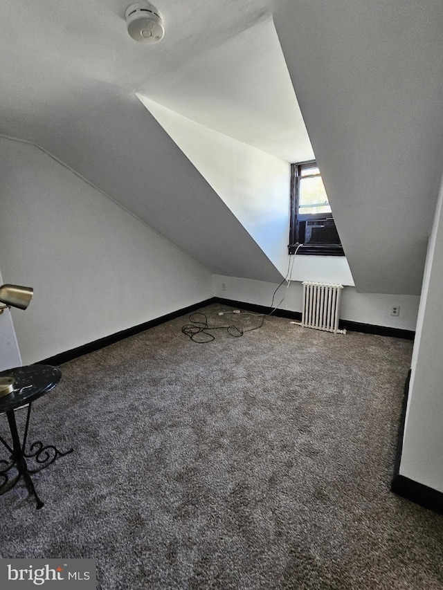 additional living space featuring radiator, cooling unit, vaulted ceiling, and dark carpet