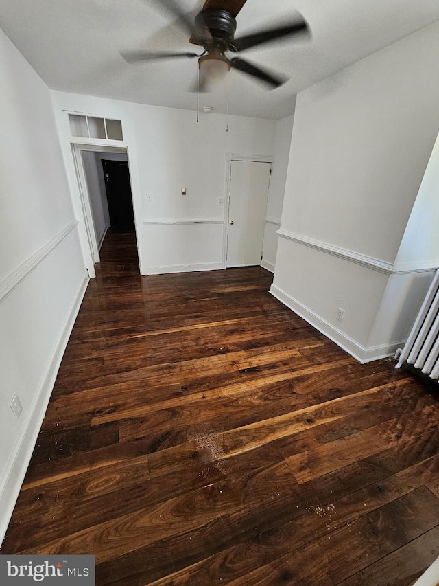 unfurnished room featuring dark hardwood / wood-style flooring, radiator, and ceiling fan