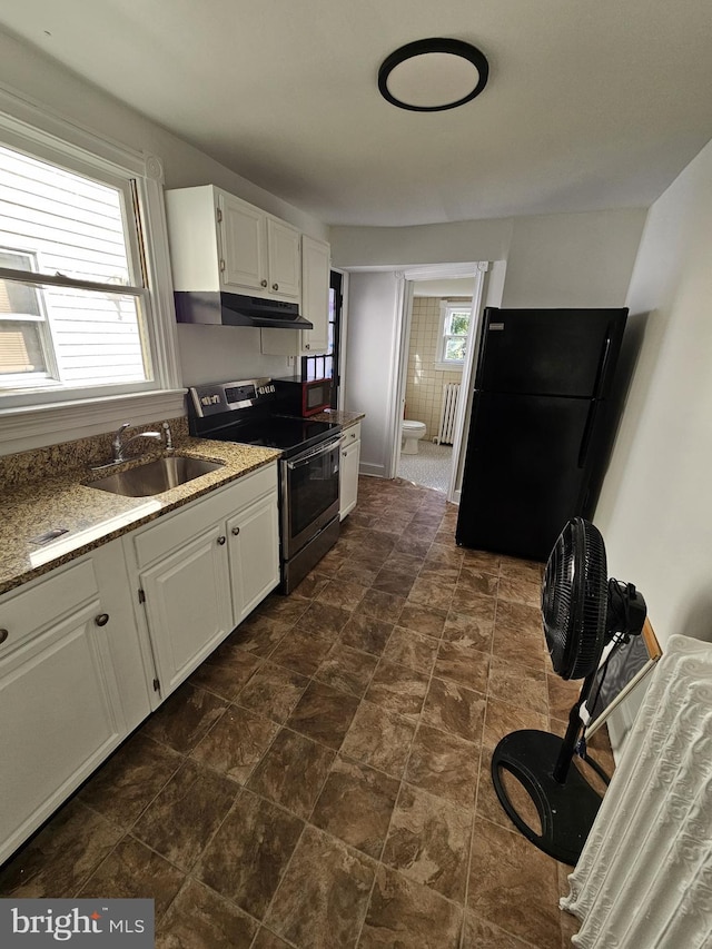 kitchen with black refrigerator, a healthy amount of sunlight, stainless steel range with electric stovetop, and sink