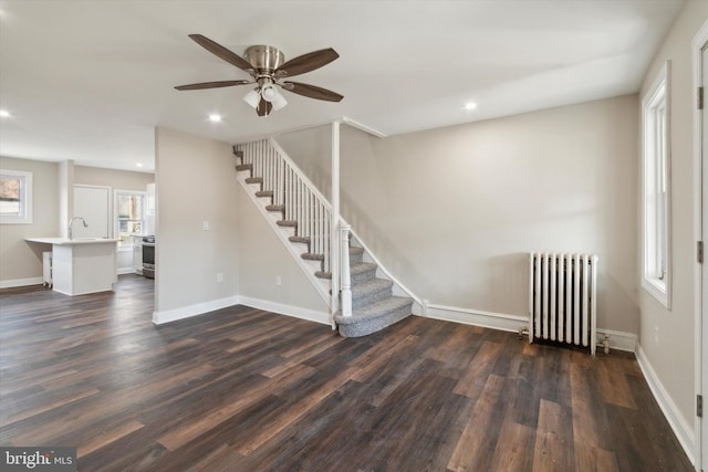 interior space with dark wood-type flooring, ceiling fan, radiator heating unit, and sink