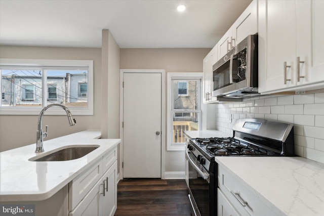 kitchen featuring white cabinetry, appliances with stainless steel finishes, dark hardwood / wood-style floors, light stone countertops, and sink