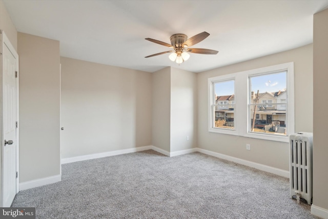 carpeted empty room with ceiling fan and radiator