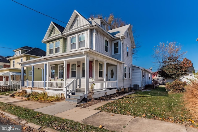 view of front of property featuring a porch, central AC, and a front lawn