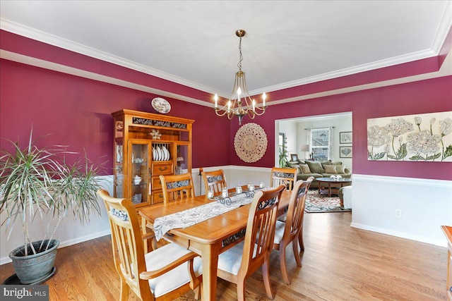 dining area with an inviting chandelier, hardwood / wood-style floors, and ornamental molding