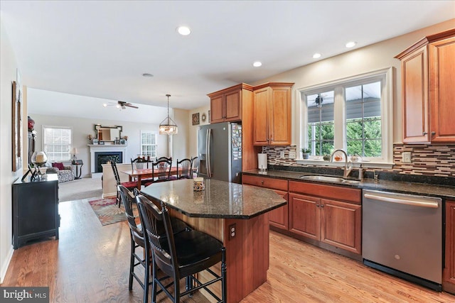 kitchen with a center island, light hardwood / wood-style flooring, hanging light fixtures, a breakfast bar, and appliances with stainless steel finishes