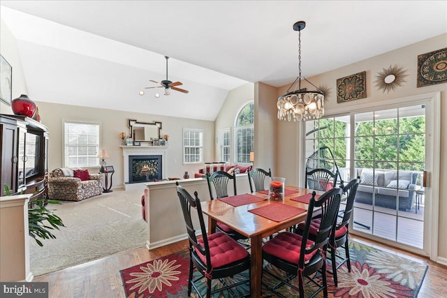 dining room featuring a wealth of natural light, ceiling fan with notable chandelier, light hardwood / wood-style floors, and vaulted ceiling