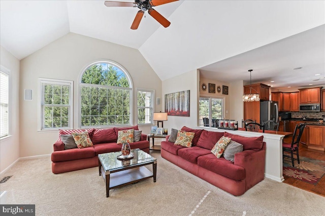 living room with light hardwood / wood-style flooring, high vaulted ceiling, ceiling fan with notable chandelier, and plenty of natural light