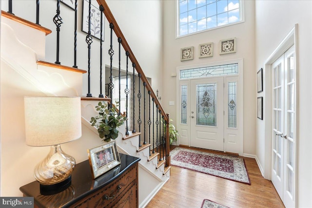 foyer entrance with a wealth of natural light, a towering ceiling, and hardwood / wood-style flooring