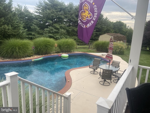 view of swimming pool with a patio area, a lawn, and a shed