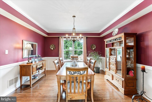 dining space featuring a notable chandelier, light wood-type flooring, and ornamental molding