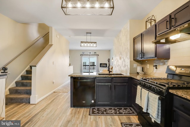 kitchen featuring sink, black appliances, dark stone countertops, light hardwood / wood-style floors, and hanging light fixtures