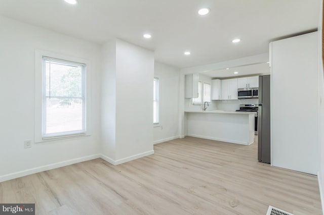 kitchen featuring white cabinetry, kitchen peninsula, sink, and light wood-type flooring