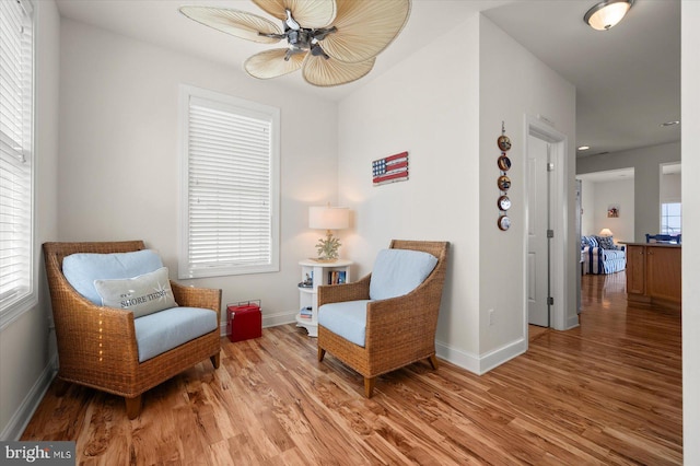 living area with ceiling fan and light hardwood / wood-style flooring