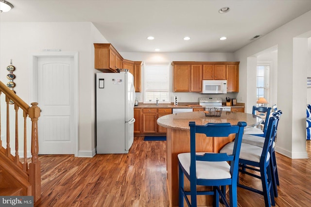 kitchen featuring white appliances, sink, dark hardwood / wood-style flooring, and a center island