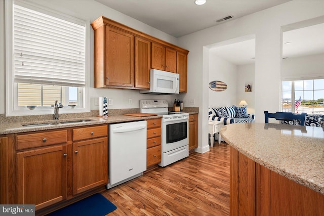 kitchen featuring white appliances, sink, light hardwood / wood-style flooring, and a wealth of natural light