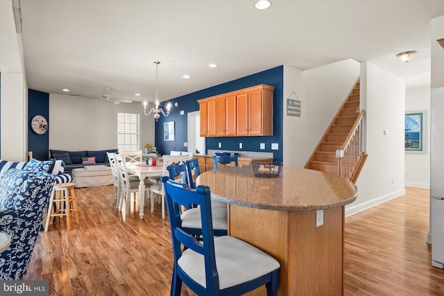 kitchen featuring light hardwood / wood-style floors, ceiling fan with notable chandelier, and decorative light fixtures