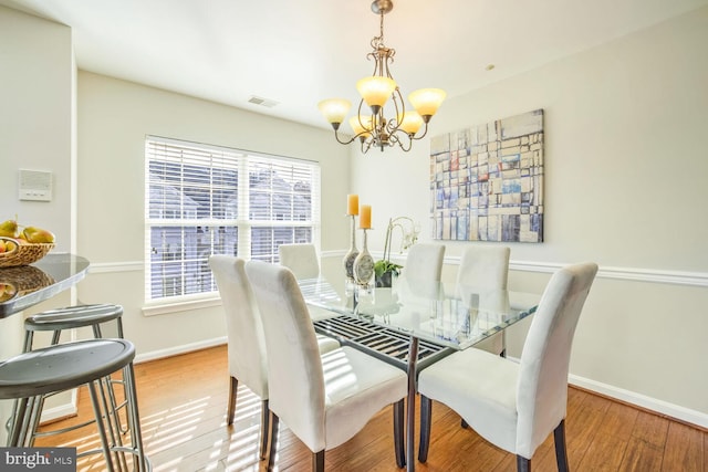 dining room with light wood-type flooring and an inviting chandelier