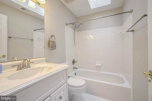 full bathroom featuring tiled shower / bath, a skylight, vanity, tile patterned floors, and toilet