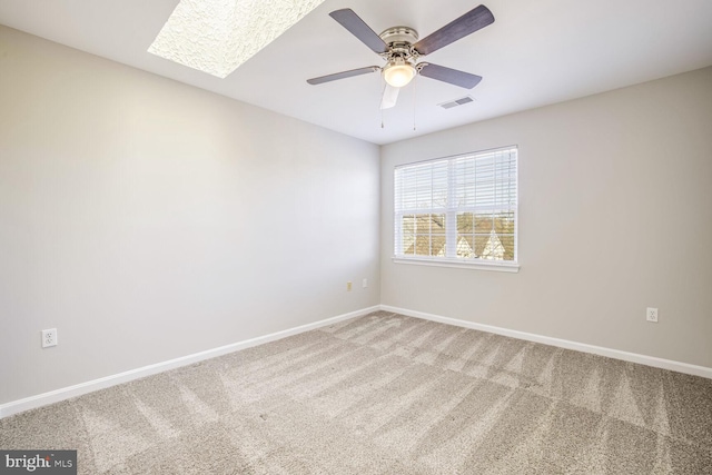 empty room with ceiling fan, a skylight, and carpet floors