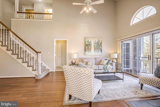 living room with a towering ceiling, hardwood / wood-style floors, and ceiling fan