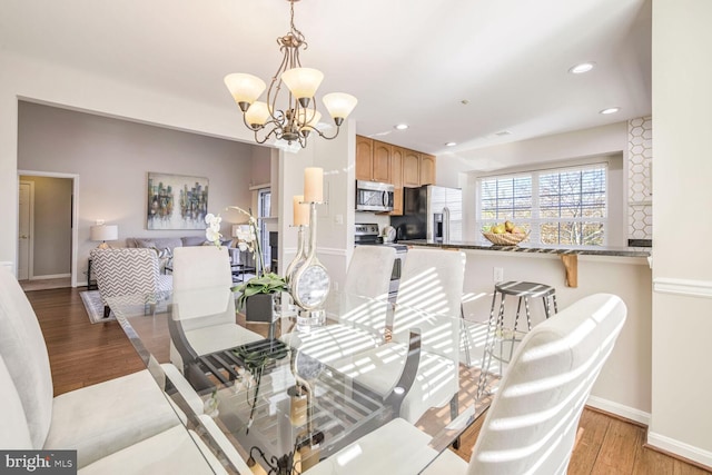 dining area with light hardwood / wood-style floors and a notable chandelier