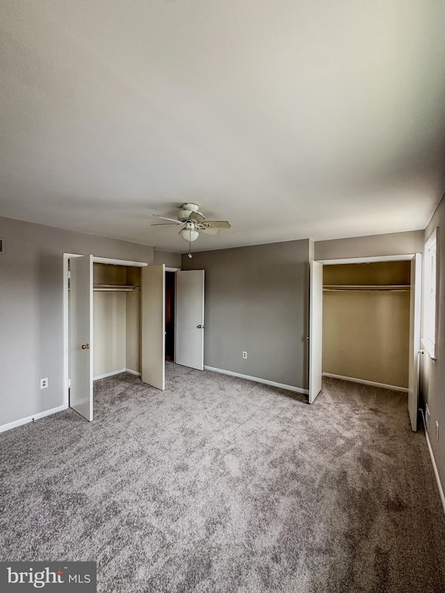 unfurnished bedroom featuring carpet flooring, two closets, and ceiling fan