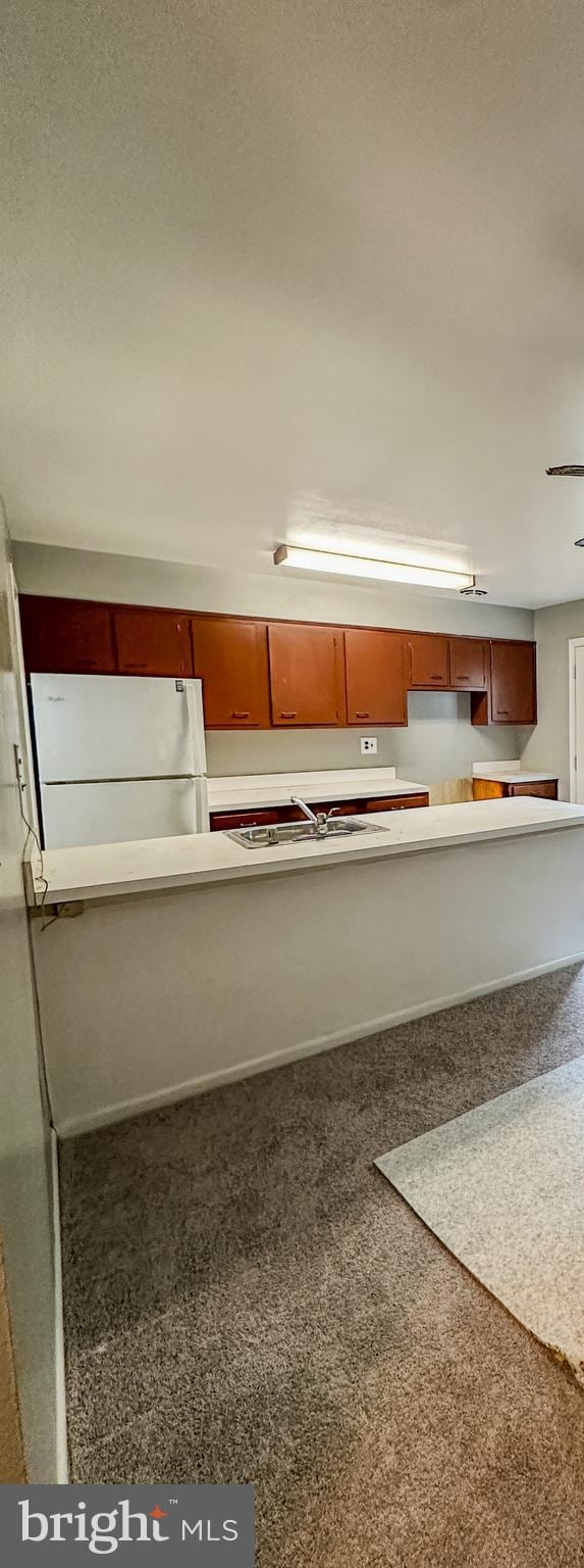 kitchen featuring carpet, sink, and white refrigerator