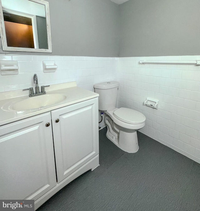 bathroom with vanity, toilet, and tile walls