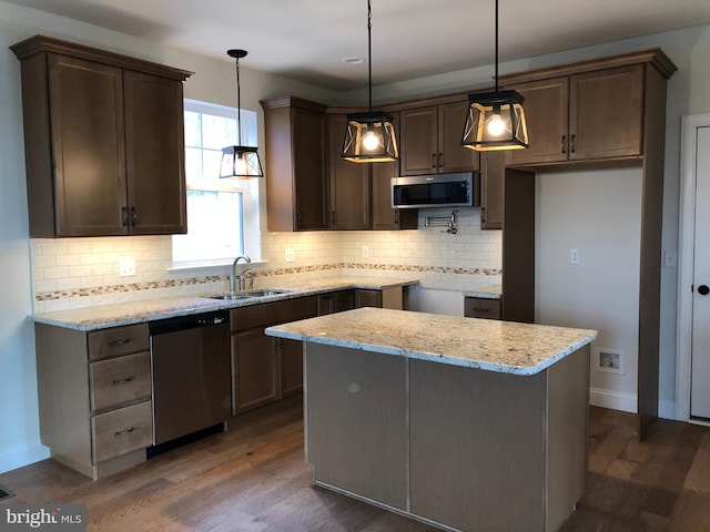 kitchen with dark wood-type flooring, light stone counters, pendant lighting, and stainless steel appliances