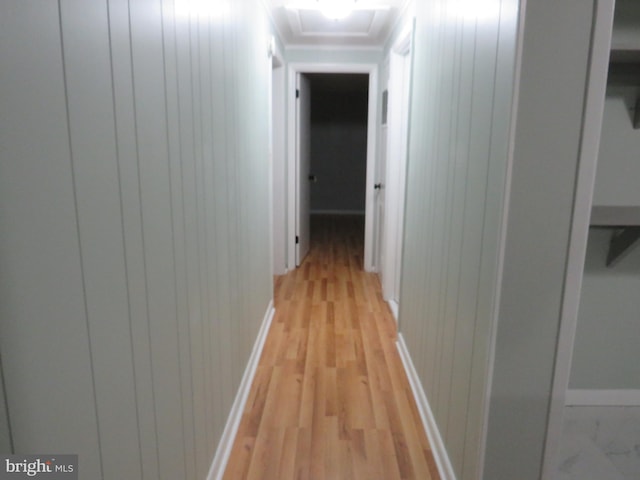 hall with light hardwood / wood-style floors and wooden walls