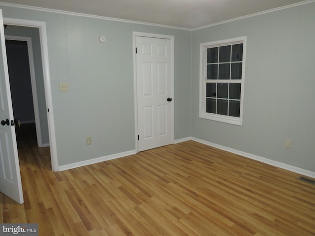 unfurnished bedroom with crown molding and light wood-type flooring