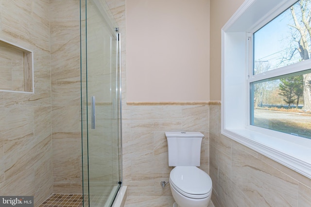 bathroom with an enclosed shower, tile walls, and toilet