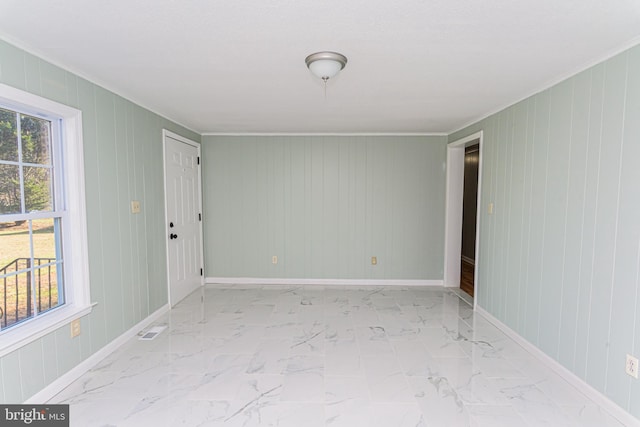 spare room with crown molding and wood walls