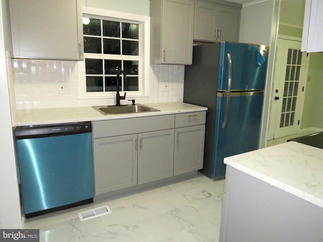 kitchen featuring black fridge, gray cabinets, stainless steel dishwasher, and sink