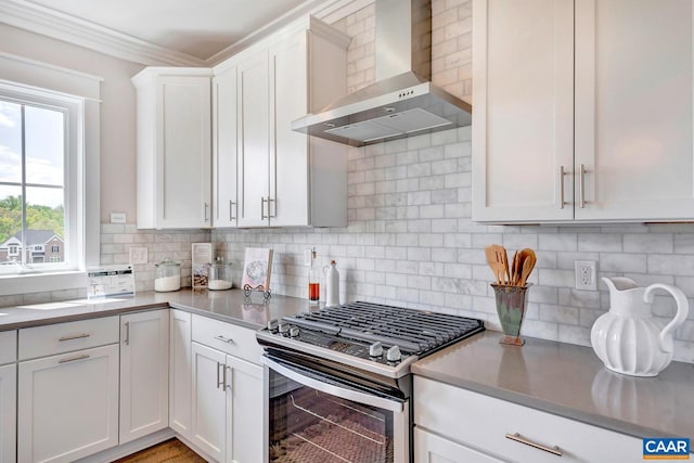 kitchen featuring ornamental molding, white cabinetry, decorative backsplash, stainless steel range with gas stovetop, and wall chimney exhaust hood