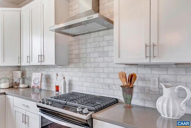 kitchen featuring stainless steel range with gas stovetop, wall chimney exhaust hood, and white cabinetry