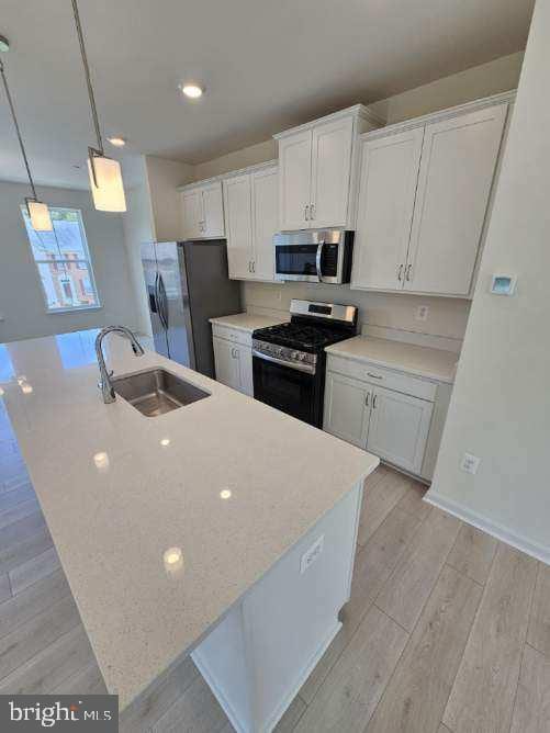 kitchen featuring decorative light fixtures, white cabinetry, sink, and stainless steel appliances