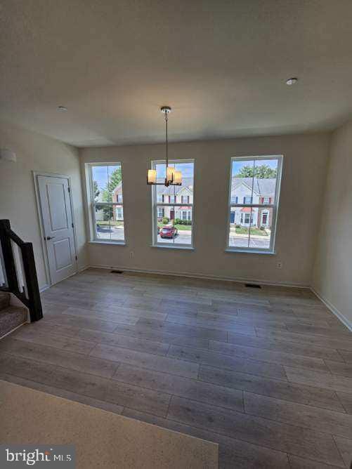 unfurnished dining area with dark hardwood / wood-style flooring and a notable chandelier