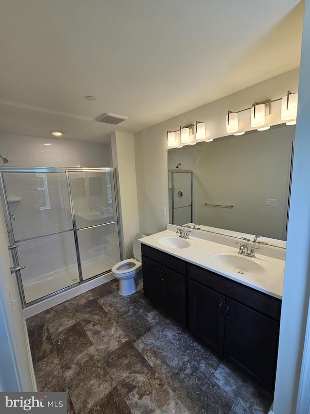 bathroom featuring toilet, vanity, and a shower with door