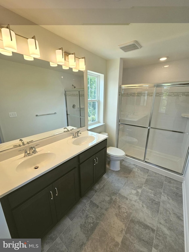 bathroom featuring vanity, toilet, and a shower with door