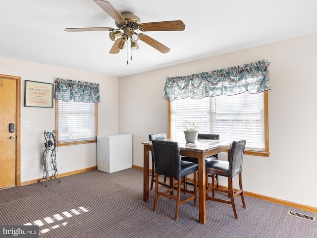 carpeted dining room featuring baseboards, visible vents, and ceiling fan